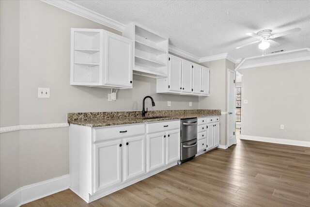 2185 Calle De Castelar, Navarre, FL 32566 - kitchen with sink, white cabinetry, wood-type flooring, ornamental molding, and dark stone counters