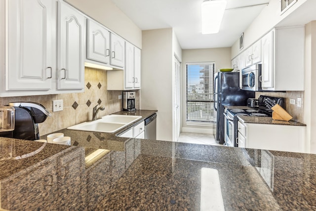 kitchen with tasteful backsplash, white cabinetry, sink, dark stone countertops, and stainless steel appliances