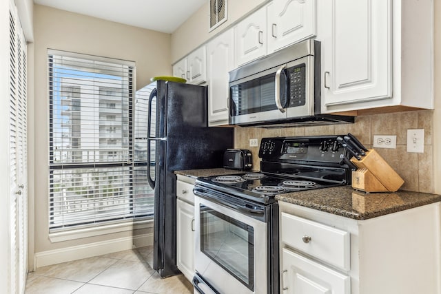 kitchen with light tile patterned flooring, appliances with stainless steel finishes, tasteful backsplash, white cabinets, and dark stone counters