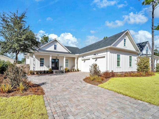 view of front of house with a garage, a front yard, and covered porch