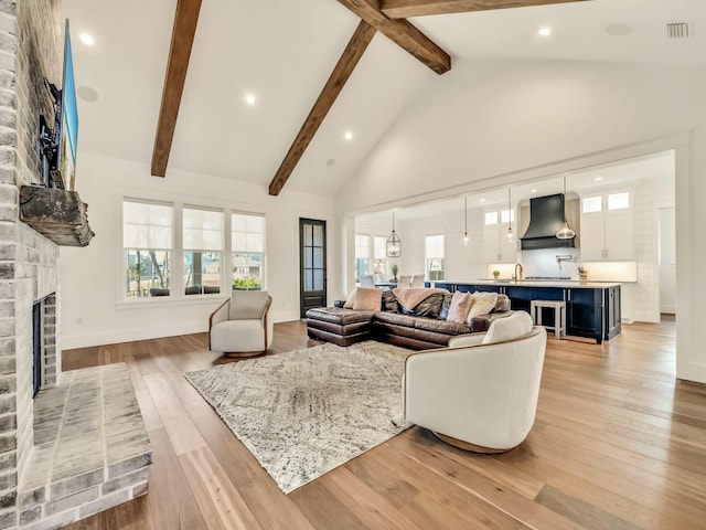 living room with beam ceiling, a fireplace, high vaulted ceiling, and light wood-type flooring