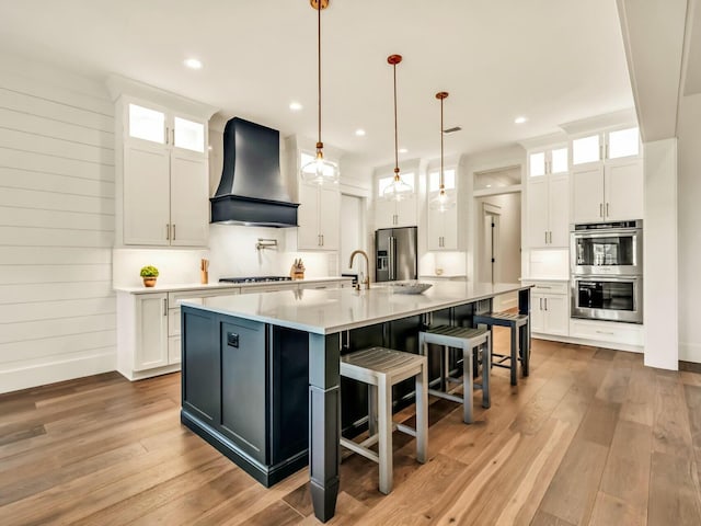 kitchen with stainless steel appliances, custom exhaust hood, and white cabinets