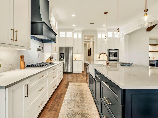 kitchen with premium range hood, stainless steel appliances, a spacious island, white cabinets, and decorative light fixtures