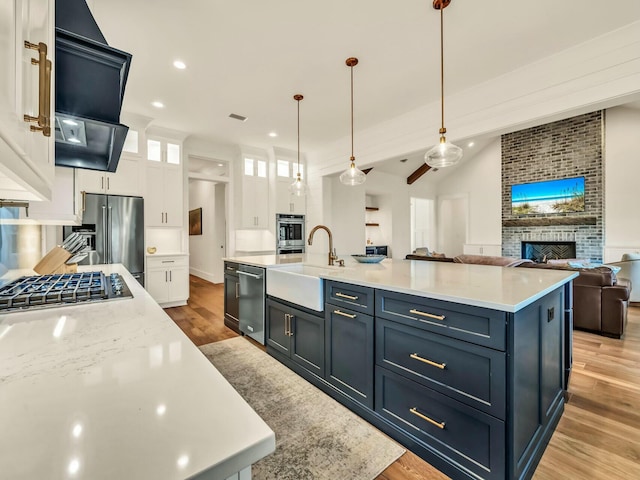 kitchen with pendant lighting, sink, a large island, appliances with stainless steel finishes, and white cabinets