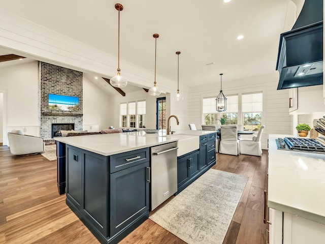 kitchen with a wealth of natural light, decorative light fixtures, dishwasher, sink, and a kitchen island with sink