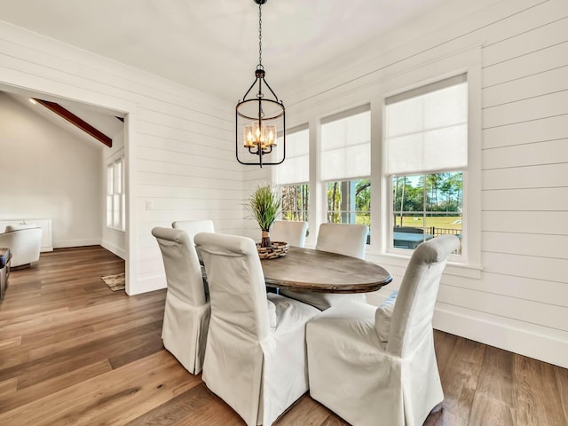 dining area featuring wooden walls, hardwood / wood-style floors, and a chandelier