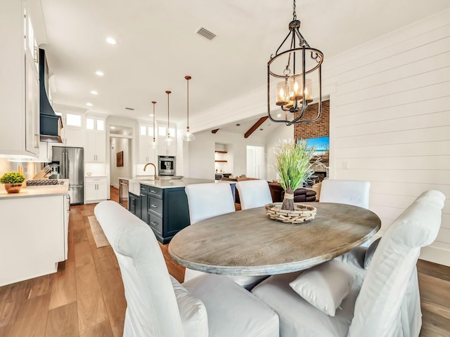 dining room with sink, a notable chandelier, and light hardwood / wood-style floors