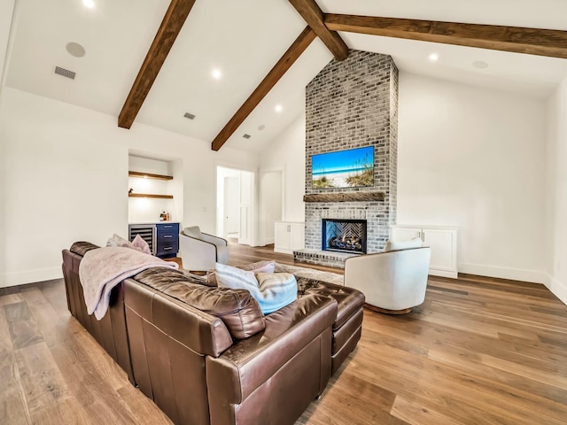 living room featuring beam ceiling, high vaulted ceiling, a fireplace, and light hardwood / wood-style floors