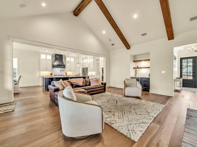 living room featuring beamed ceiling, an inviting chandelier, high vaulted ceiling, and light hardwood / wood-style flooring