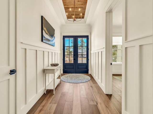 doorway to outside with french doors, crown molding, a raised ceiling, a wealth of natural light, and light hardwood / wood-style floors