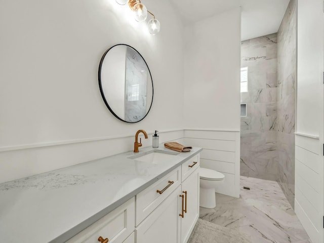 bathroom with tiled shower, vanity, and toilet