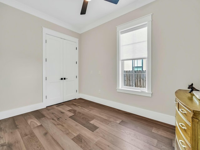 unfurnished bedroom with ceiling fan, ornamental molding, light hardwood / wood-style floors, and a closet