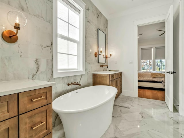 bathroom featuring vanity, a bath, and tile walls