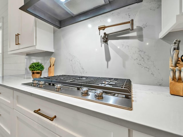 kitchen featuring white cabinetry, decorative backsplash, light stone countertops, and stainless steel gas stovetop