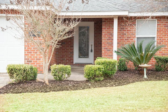 property entrance with a garage and a lawn