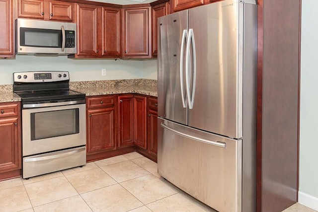 kitchen with stainless steel appliances, light tile patterned floors, and light stone counters