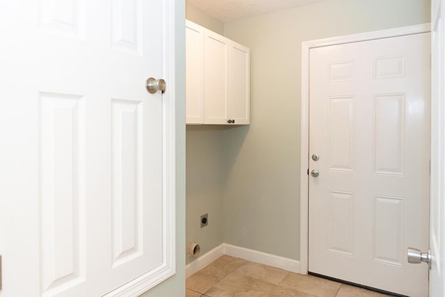 washroom with electric dryer hookup, light tile patterned floors, cabinets, and a textured ceiling