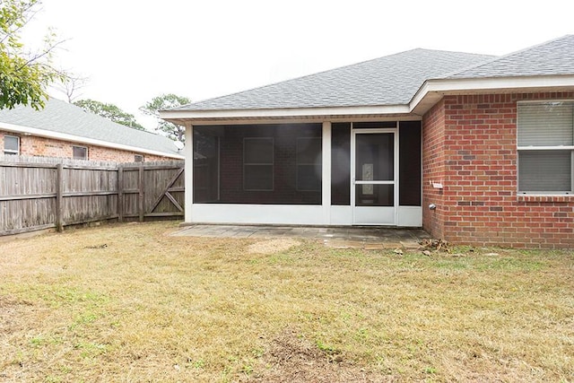 rear view of house with a yard and a sunroom