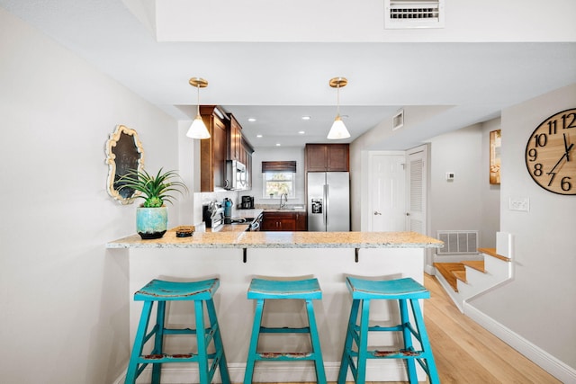 kitchen featuring a peninsula, light wood-style flooring, visible vents, and stainless steel appliances