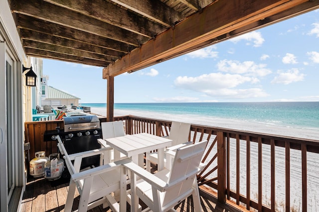 wooden terrace with area for grilling, a beach view, and a water view