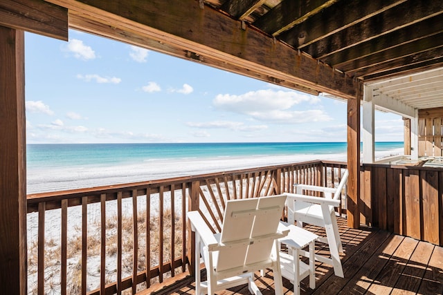 wooden terrace with a water view and a view of the beach