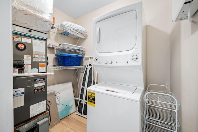 laundry area featuring stacked washer and clothes dryer, wood finished floors, and laundry area