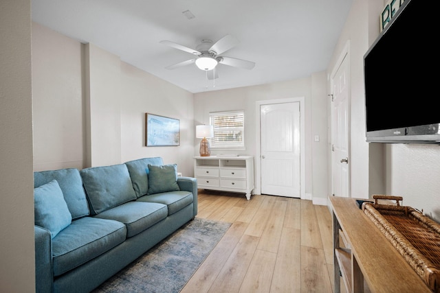 living area featuring baseboards, light wood-style floors, and ceiling fan