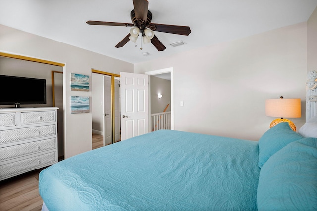 bedroom with visible vents, two closets, wood finished floors, and a ceiling fan