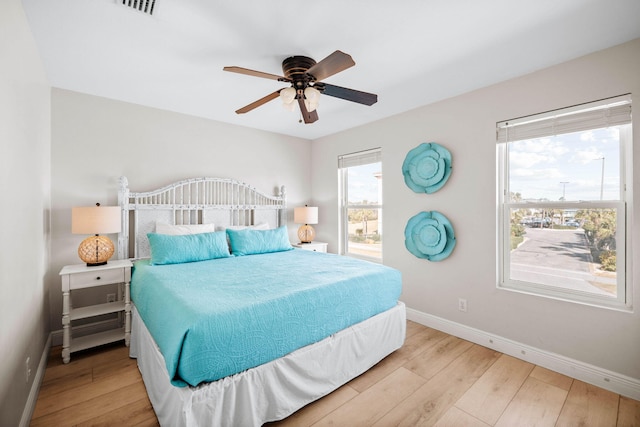 bedroom featuring ceiling fan, visible vents, baseboards, and wood finished floors