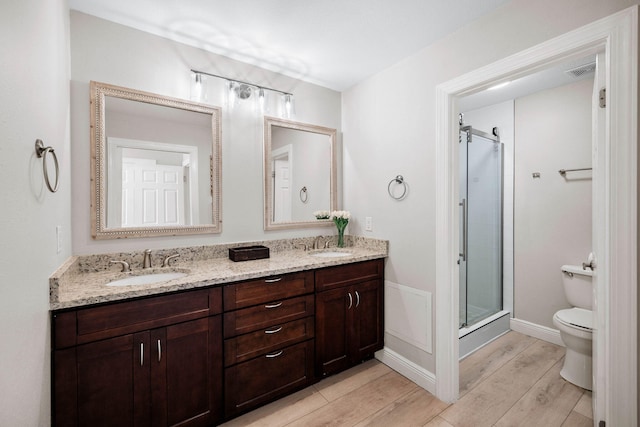 bathroom with a shower stall, toilet, visible vents, and a sink