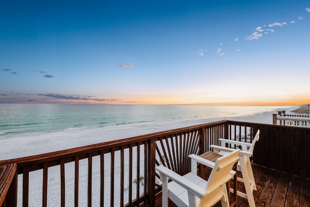 deck at dusk with a water view and a beach view