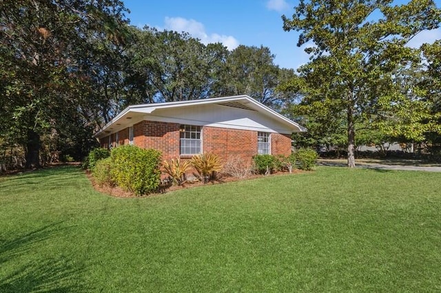 view of home's exterior with brick siding and a lawn