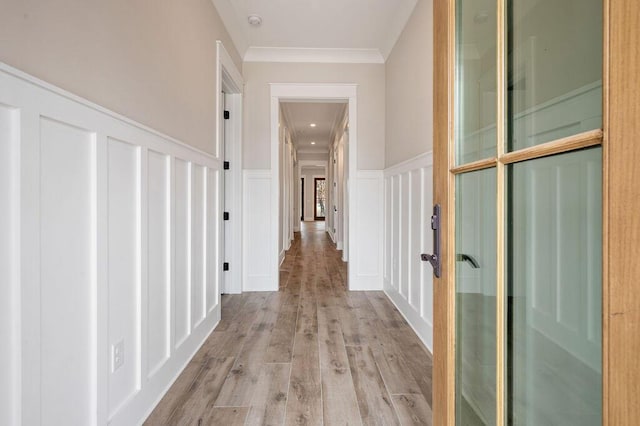 hallway featuring ornamental molding and light hardwood / wood-style flooring