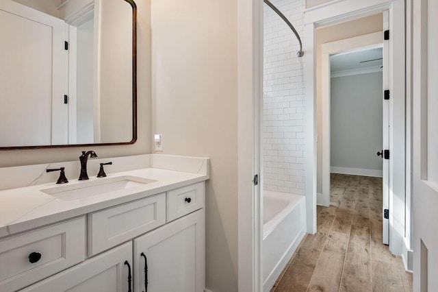 bathroom featuring tiled shower / bath combo, vanity, ornamental molding, and hardwood / wood-style floors