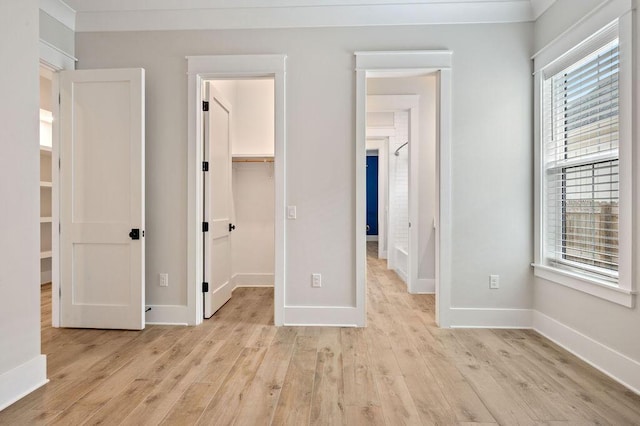 unfurnished bedroom featuring a walk in closet, a closet, and light hardwood / wood-style flooring