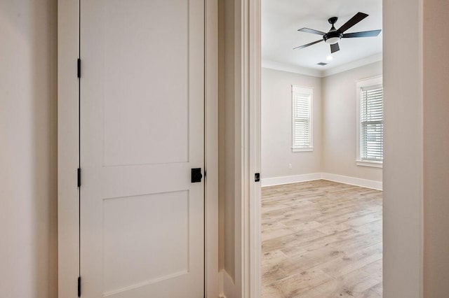 corridor with ornamental molding and light hardwood / wood-style floors