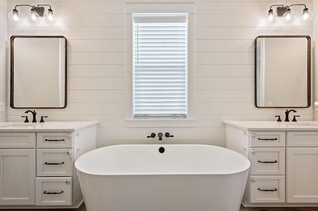 bathroom featuring a washtub, vanity, and wooden walls