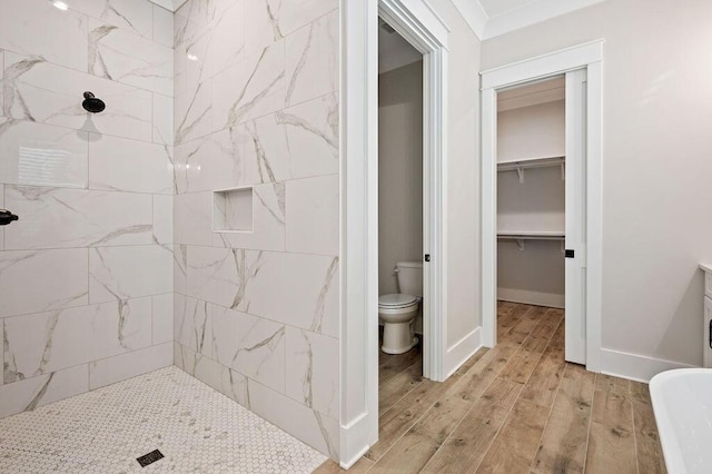 bathroom featuring wood-type flooring, a tile shower, and toilet