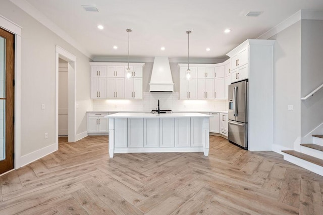 kitchen featuring decorative light fixtures, stainless steel fridge with ice dispenser, custom exhaust hood, and white cabinets