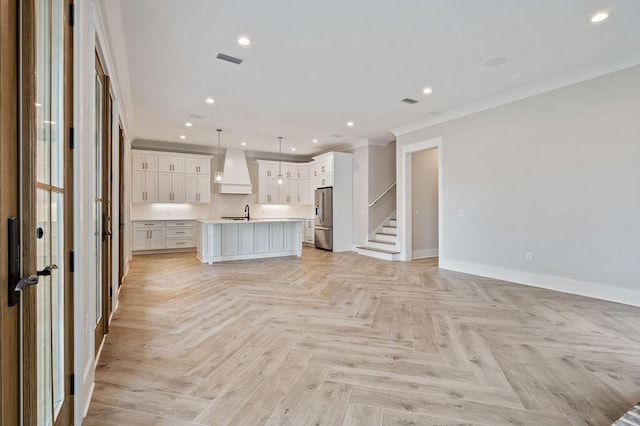 unfurnished living room with ornamental molding, sink, and light parquet flooring