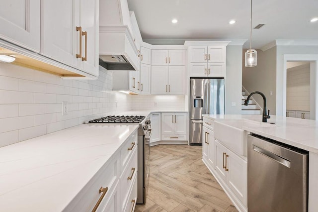 kitchen featuring hanging light fixtures, stainless steel appliances, sink, and white cabinets