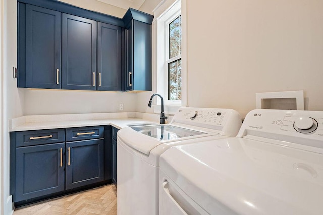 laundry area with sink, light parquet flooring, cabinets, and washing machine and clothes dryer