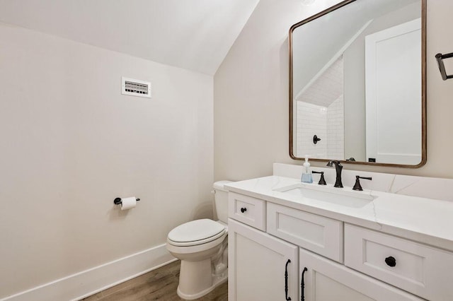 bathroom featuring wood-type flooring, toilet, vaulted ceiling, and vanity