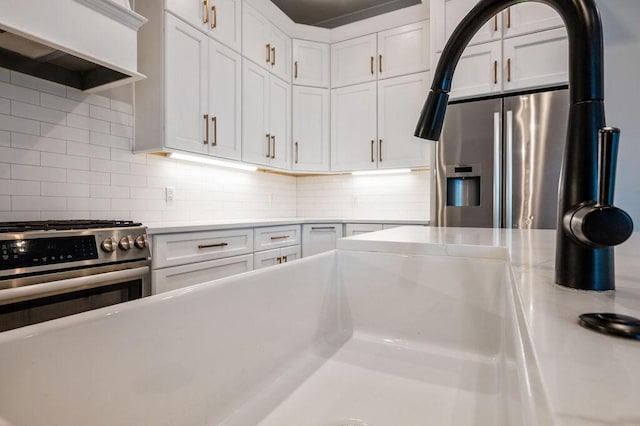 kitchen featuring backsplash, stainless steel range with gas cooktop, white cabinets, and premium range hood