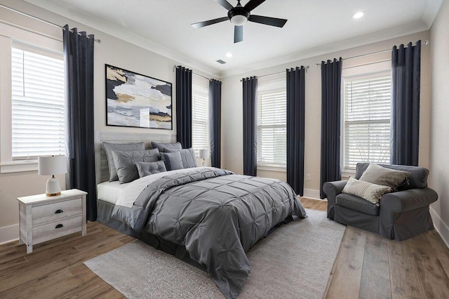 bedroom with hardwood / wood-style floors, ornamental molding, and ceiling fan