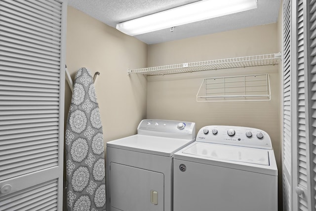 clothes washing area with laundry area, a textured ceiling, and independent washer and dryer