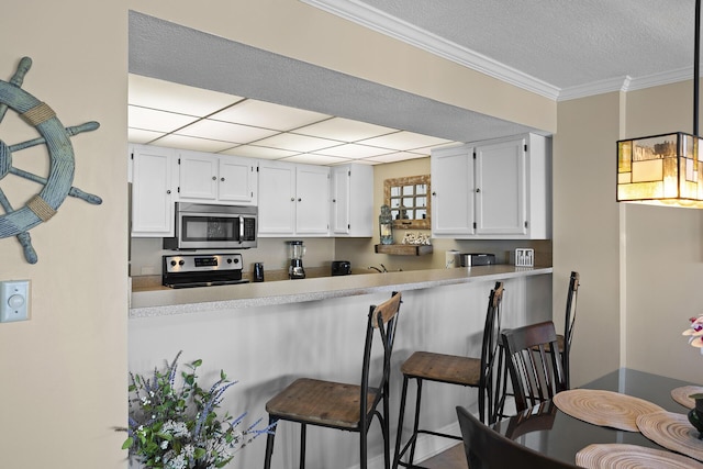 kitchen with stainless steel appliances, light countertops, white cabinetry, and a kitchen breakfast bar