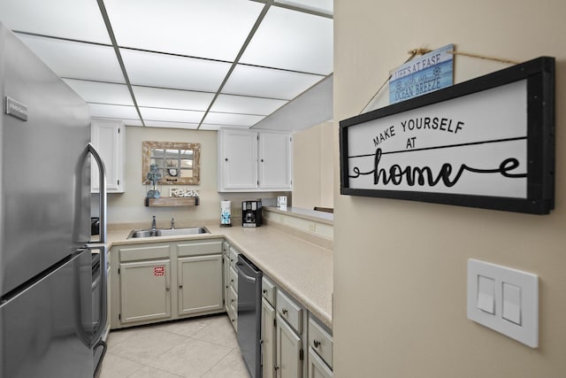 kitchen with light tile patterned floors, light countertops, appliances with stainless steel finishes, and a sink