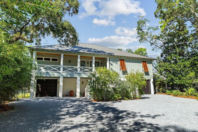 view of front of home with a garage, gravel driveway, metal roof, and a standing seam roof