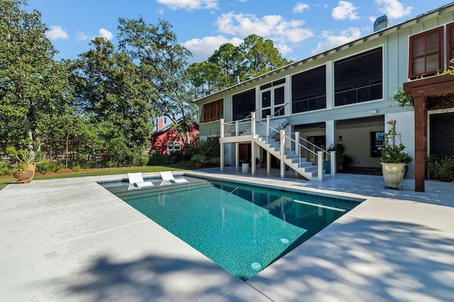 outdoor pool with a sunroom, a patio, and stairs